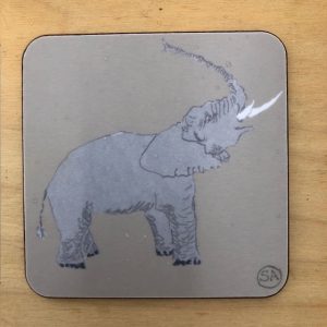 elephant coaster, raising its trunk in the air, on a warm grey melamine background , backed in cork