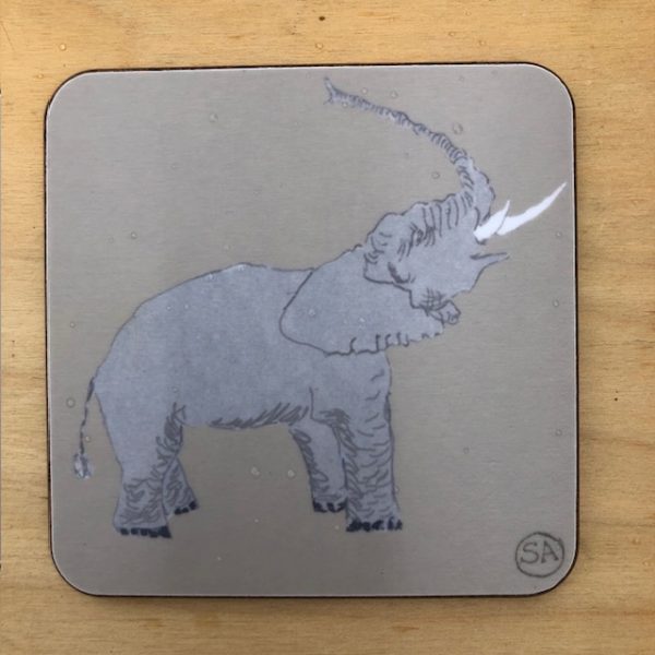 elephant coaster, raising its trunk in the air, on a warm grey melamine background , backed in cork