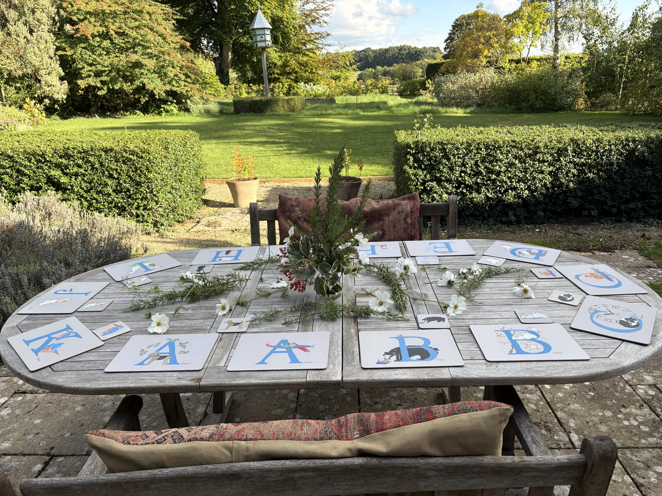a photo of a table in a garden laid out with illustrated alphabet letter placemats