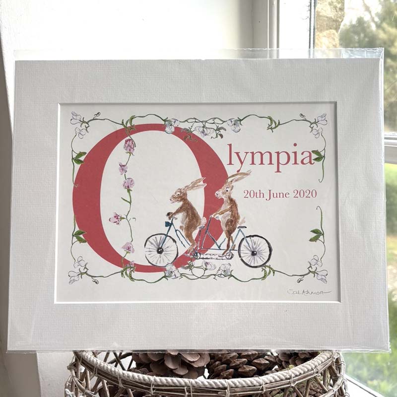 2 hares zoom around on a tandem through the letter O for Olympia, drapped with sweetpeas